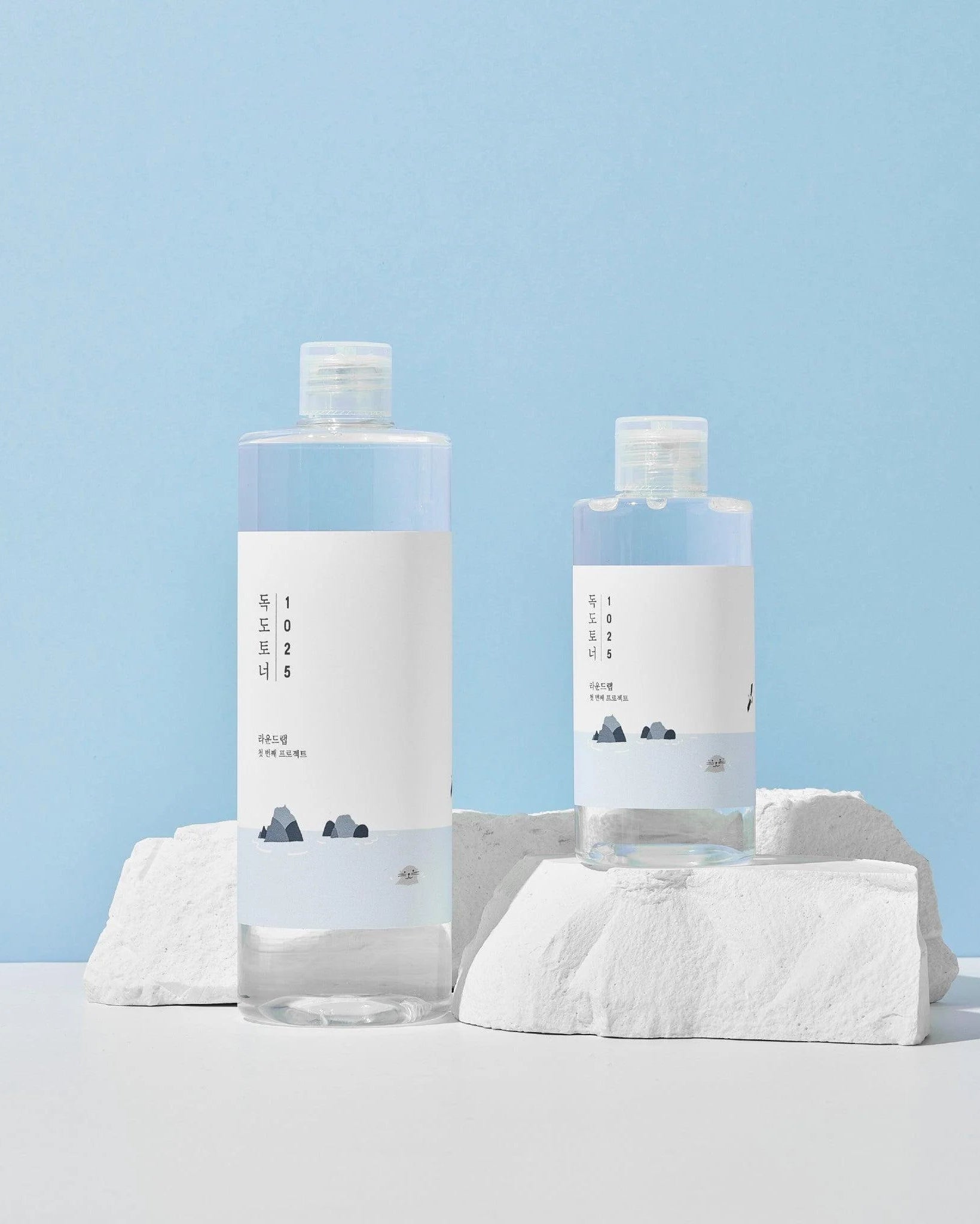 Two skincare bottles on a light blue background
