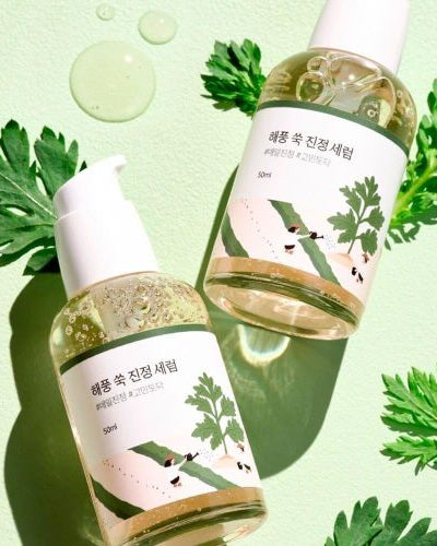 Two skincare bottles with green leaves and bubbles on a light green background