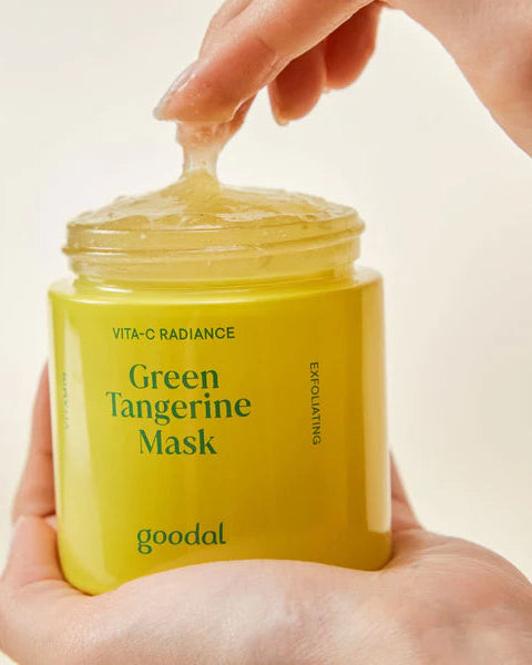 Yellow jar of 'Green Tangerine Mask' by goodal held by a hand against a beige background