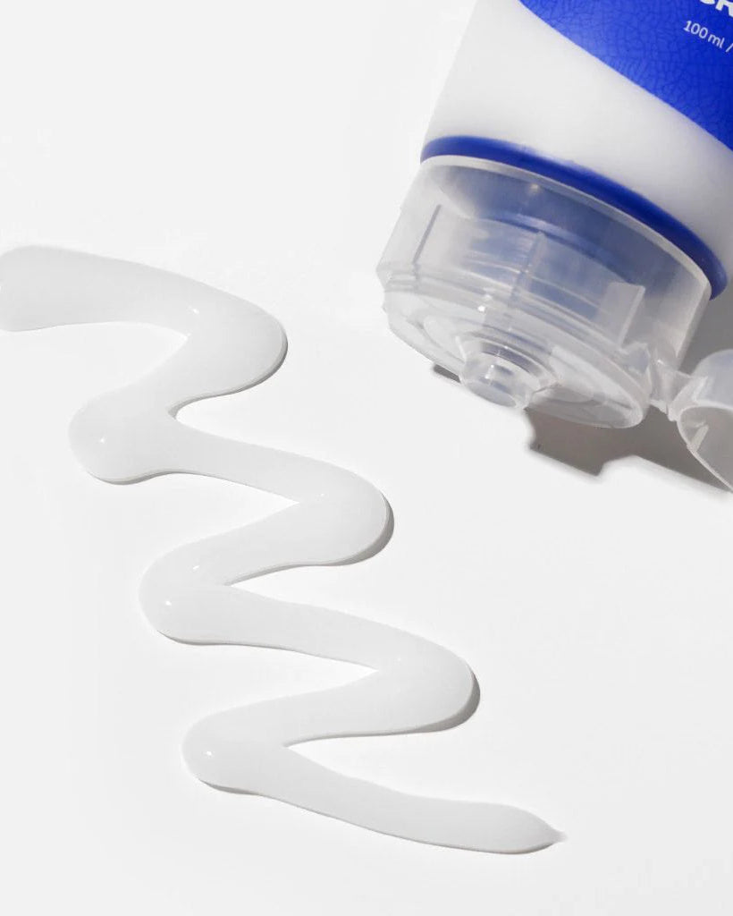 White cream being squeezed from a blue and white tube on a light gray background