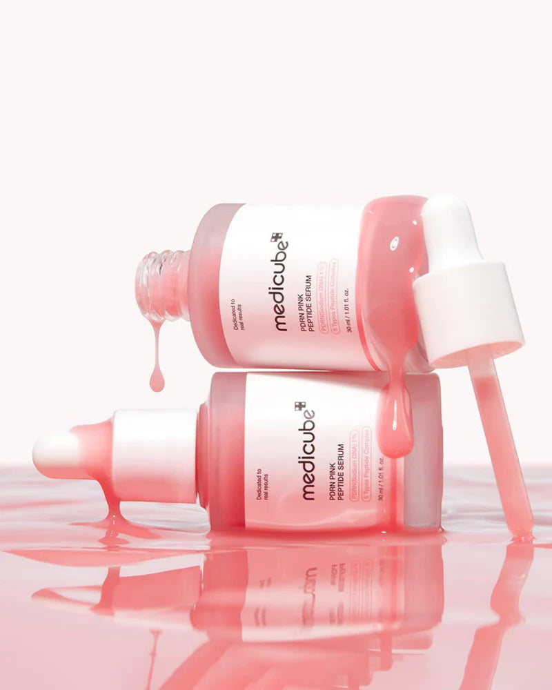 TwoMedicube skincare bottles with pink liquid on a white background