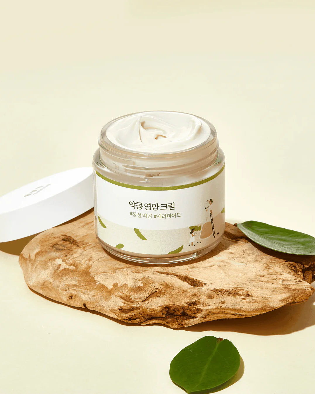 Jar of cream on a wooden surface with green leaves